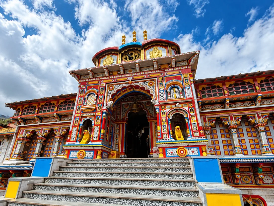 The brightly painted facade of the Badrinath temple above its steps, under a blue sky
