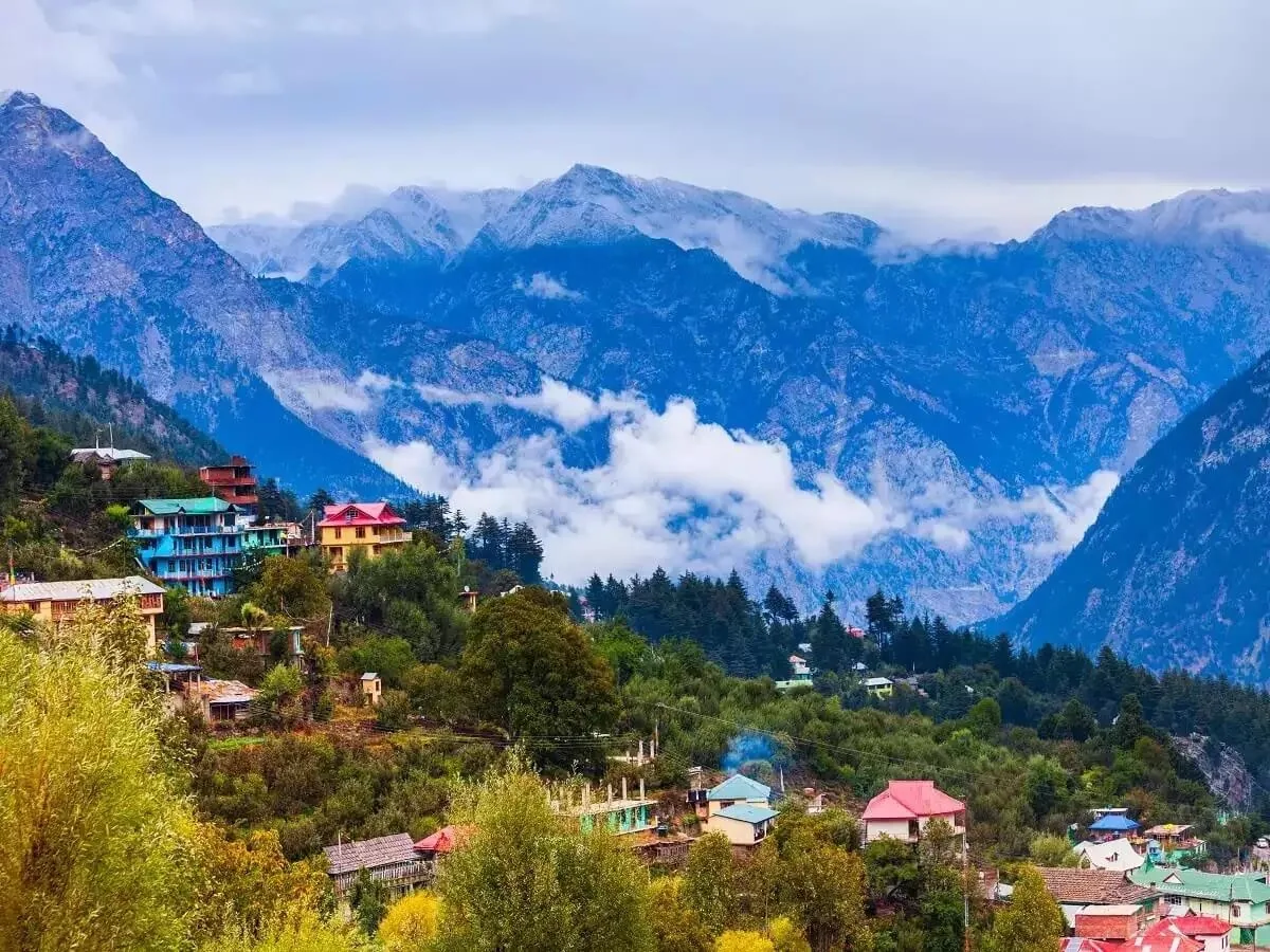 A Chakrata hillside village of painted roofs among deodars, snow peaks behind