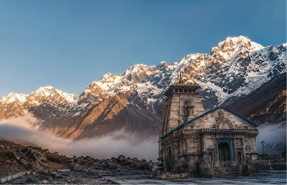 A stone Himalayan temple at first light below a snow-covered ridge