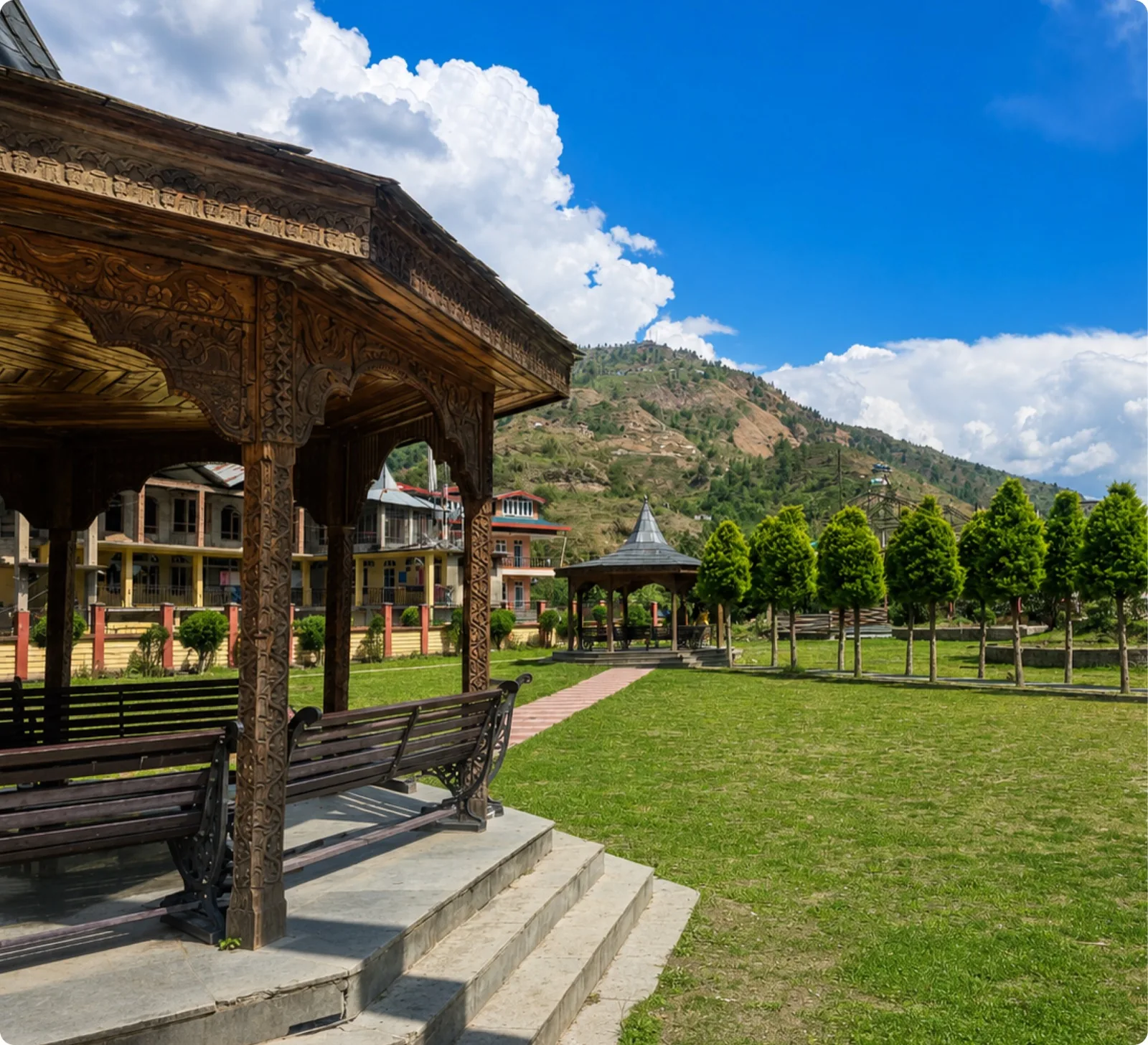 A carved wooden pavilion in a hill-town garden below the mountains