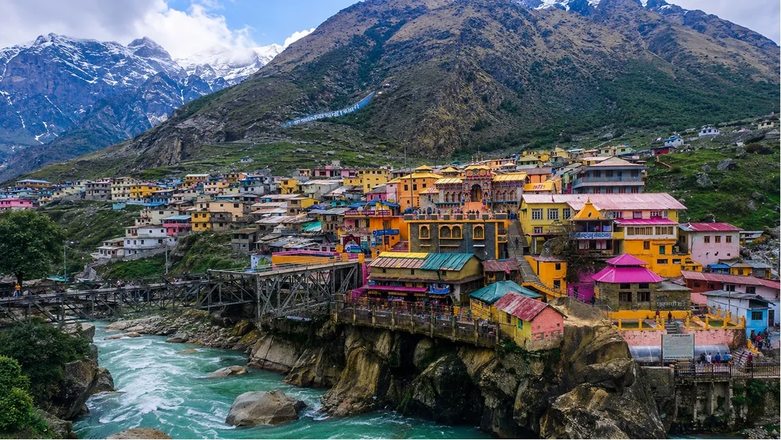 Brightly painted houses stacked on a rock bluff above a fast turquoise river