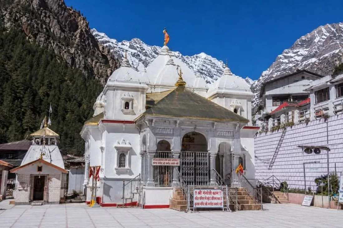 The whitewashed Gangotri temple with snow-covered ridges rising behind it