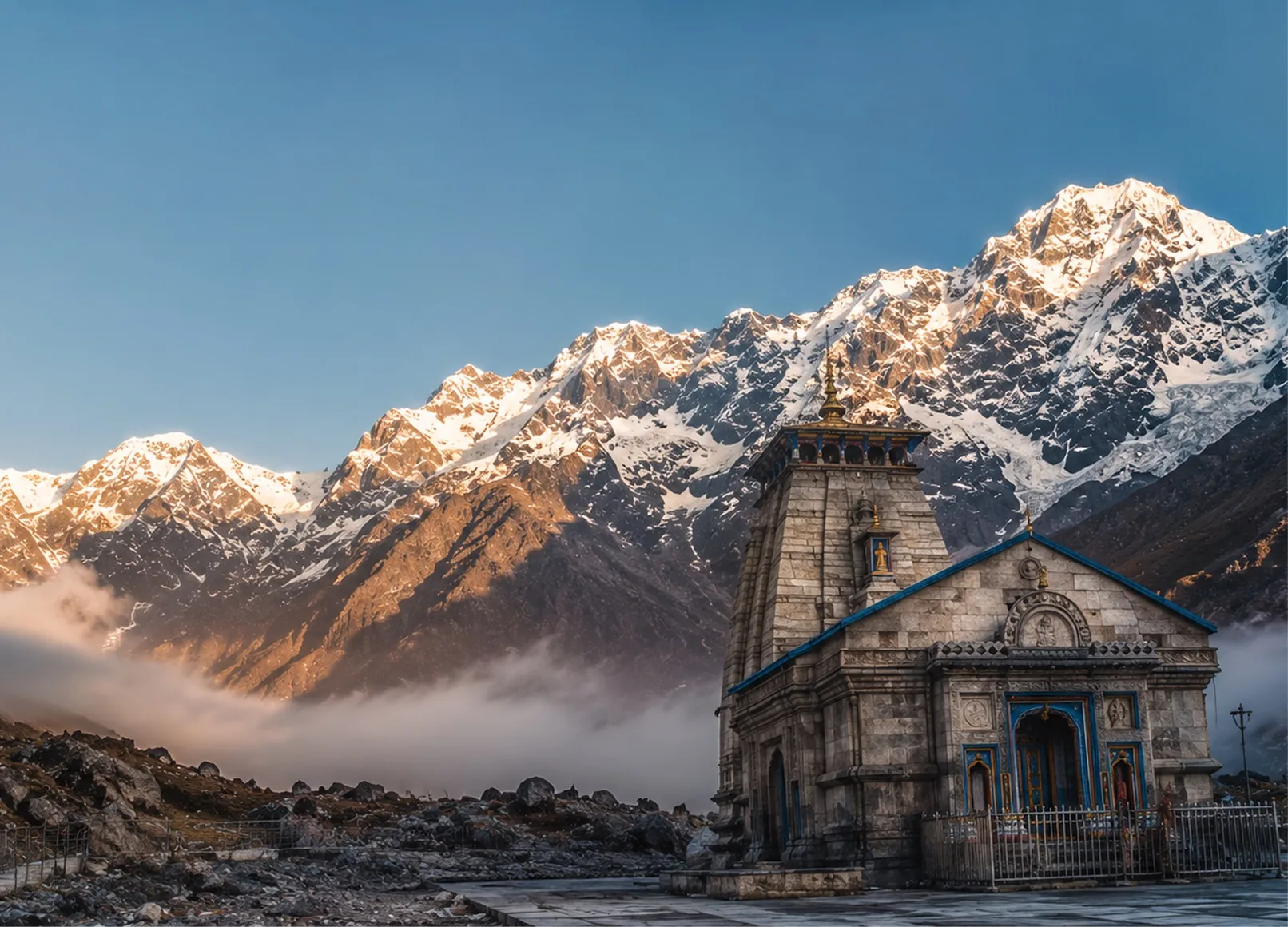 A stone Himalayan temple at first light, a snow-covered ridge catching the sun behind it