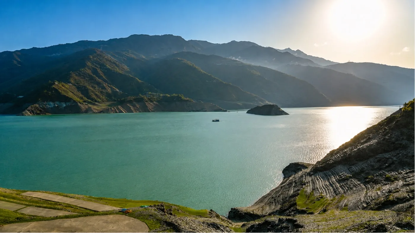 Turquoise reservoir winding between steep green mountain slopes